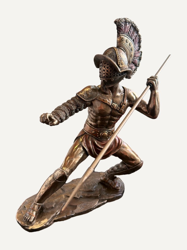 Gladiatore romano in resina effetto bronzo, in affondo d'attacco: elmo con cresta e visiera a grata, protezione a segmenti sul braccio, lunga lancia tenuta in diagonale