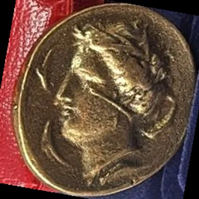 Real photo taken in our shop: gold-coloured replica with the head of Arethusa facing left, wearing a wreath of leaves, with dolphins around.
