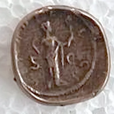 Modern replica of a Roman bronze coin with a woman’s portrait, not identified, the figure: A standing figure with a long staff and outstretched arm, between S and C. Indicative photo of the replica on sale in the shop, bronze-coloured.
