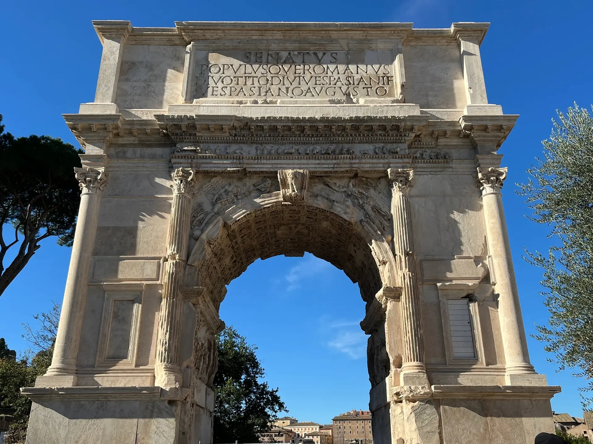 The Arch of Titus from the Colosseum side, photograph of 28 November 2025: in the centre the ancient marble with the dedication SENATVS POPVLVSQVE ROMANVS, at the sides and in most of the attic the travertine of the 1822 restoration.