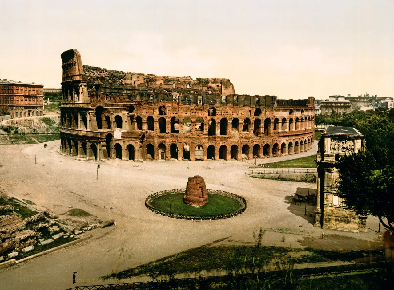 Colour photograph from about 1880-1890: the Colosseum and, in front, the brick cone of the Meta Sudans still standing.