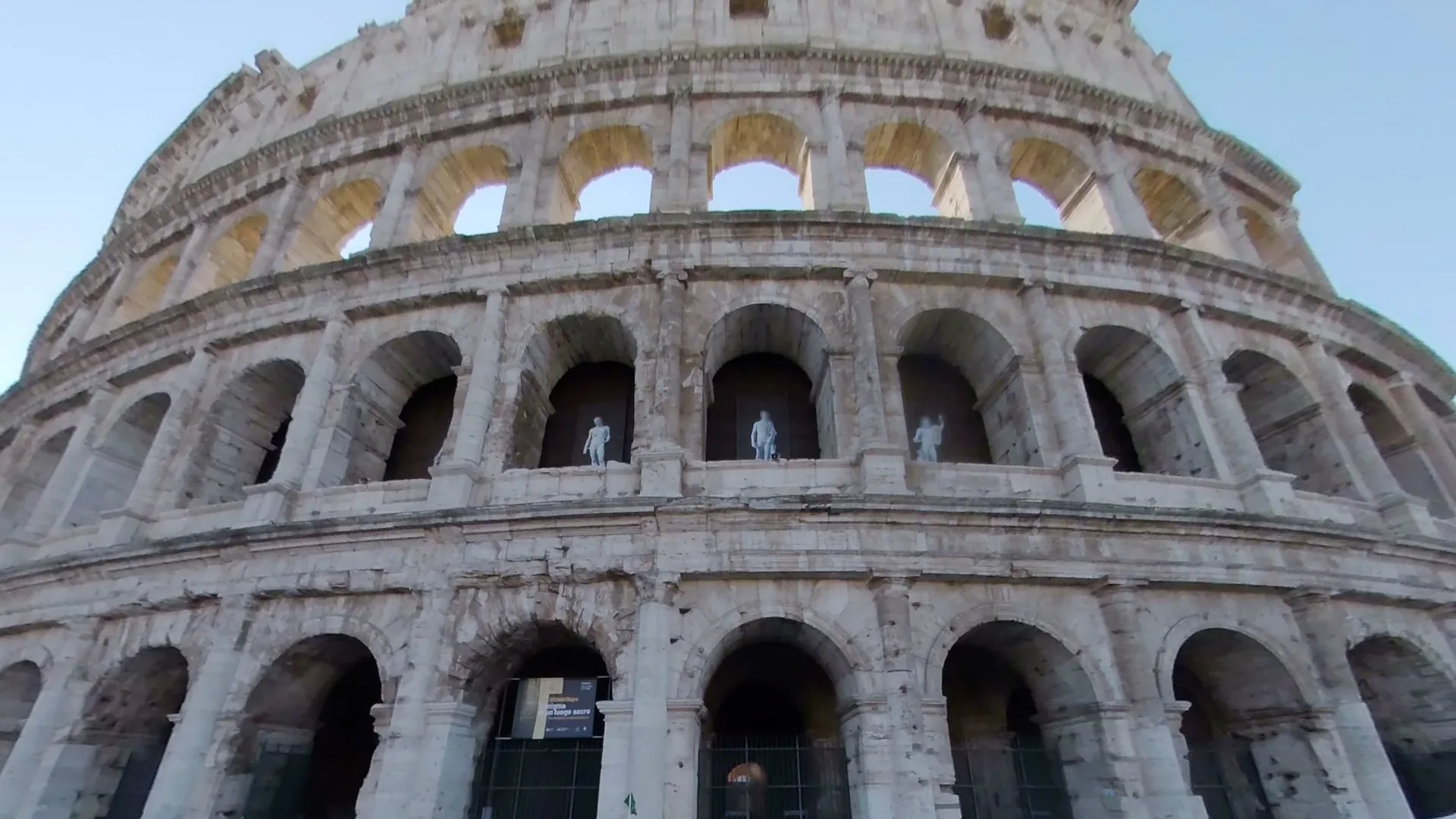 The north front of the Colosseum seen from below, photograph of 6 March 2025. In the photograph, three arches of the second storey have white statues.