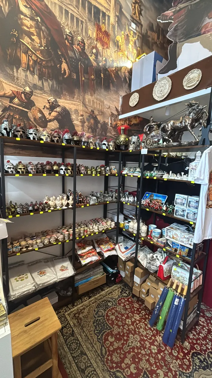 Inside the Imperivm Art shop: shelves of Roman reproductions, helmets and figurines below a large mural of legionaries.