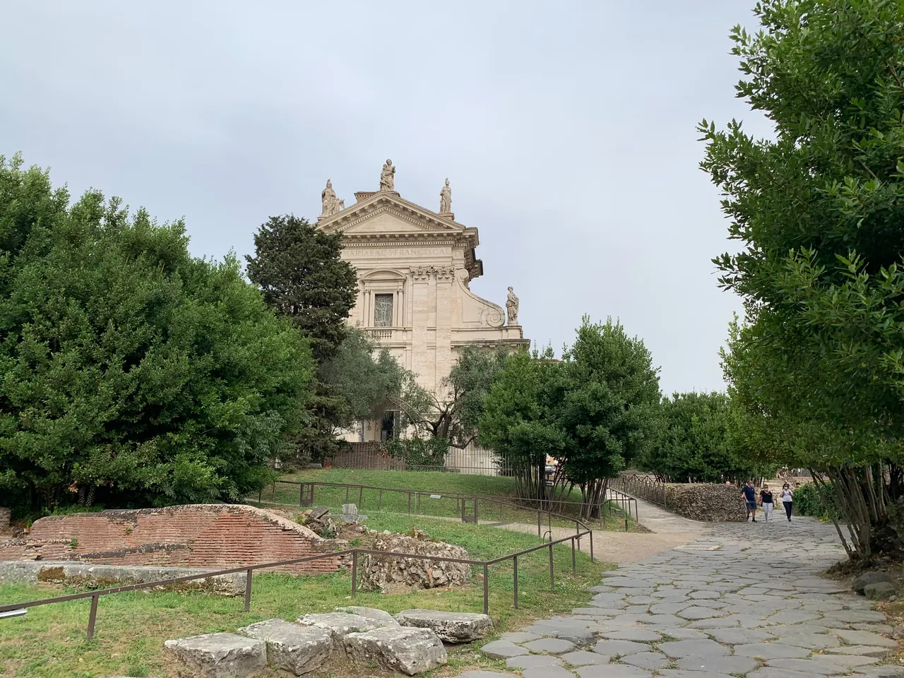 The large paving stones of the Sacred Way climbing between trees and railings.