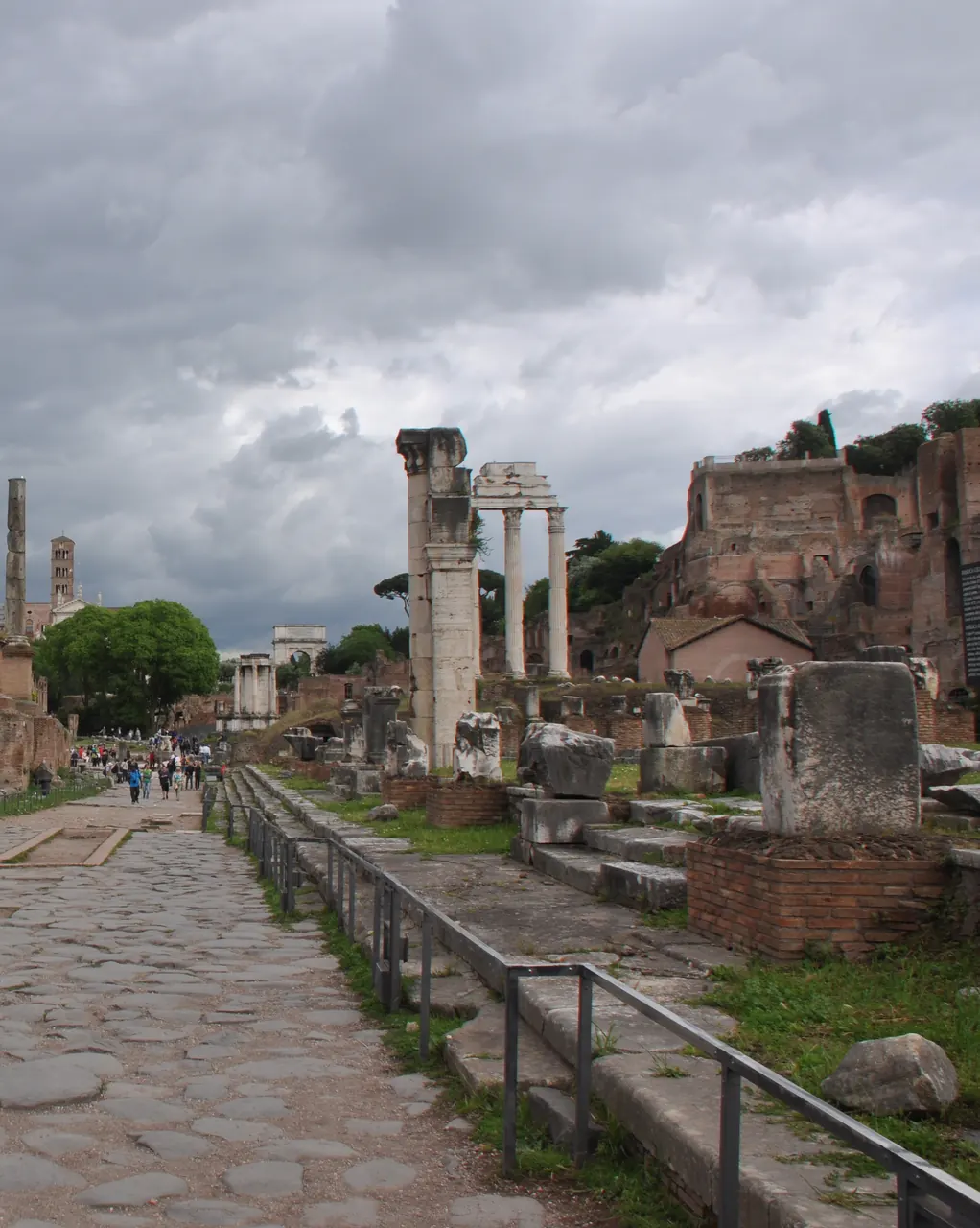 The Sacred Way in the Roman Forum, a stone road through the ruins, with the Arch of Titus small in the distance.